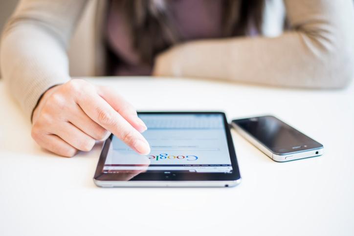 Person scrolling tablet with Google logo on screen