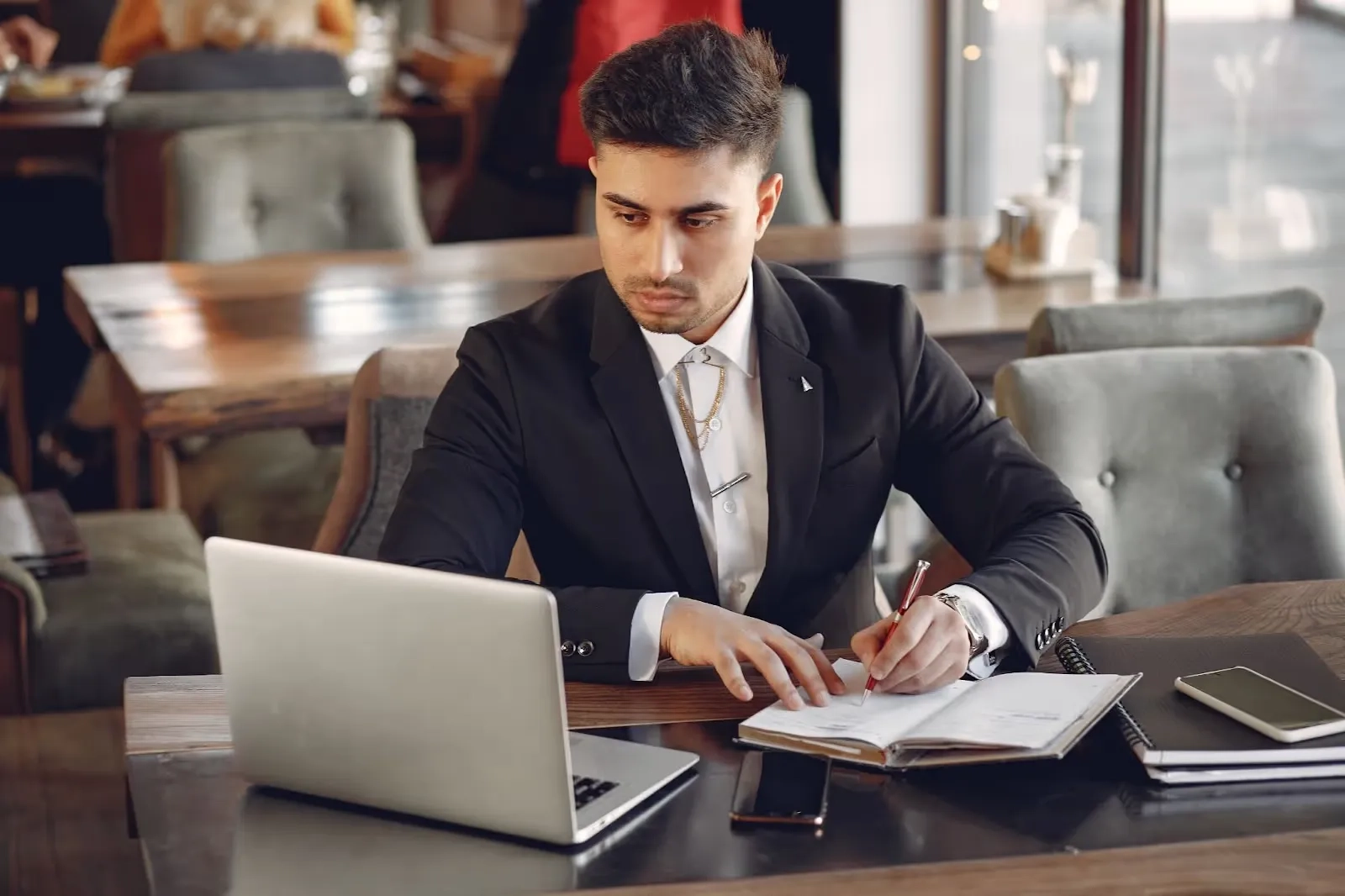 person in front of laptop taking notes