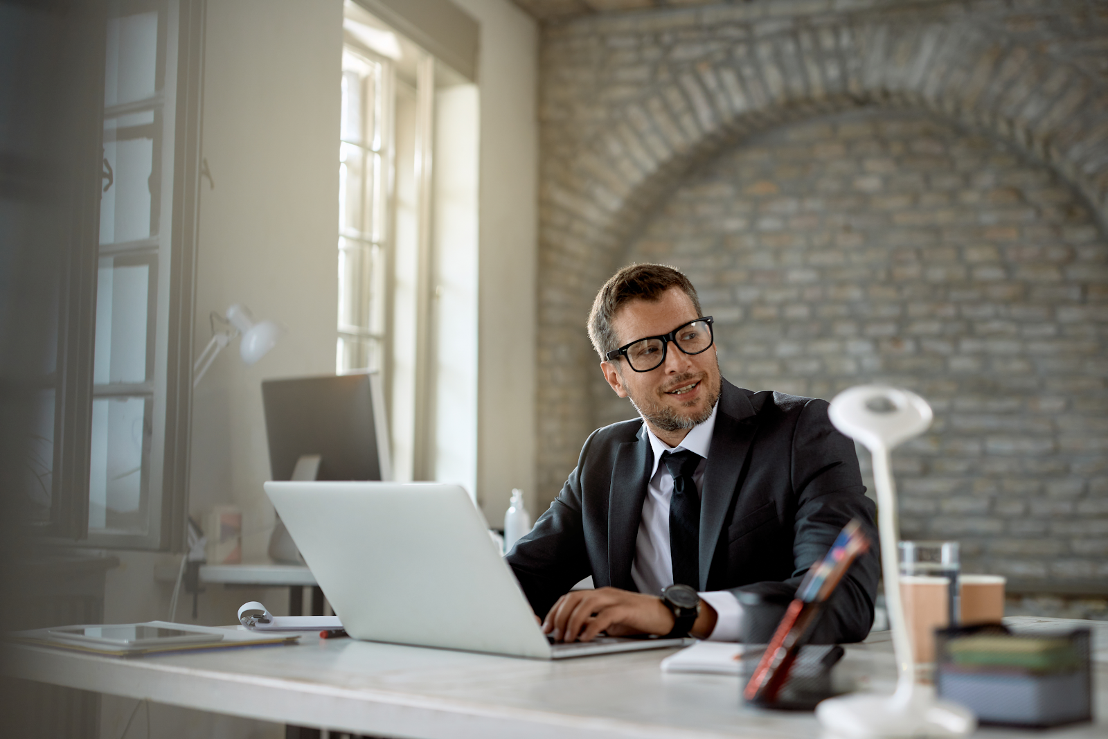 person with glasses sitting in an office in front of a lap top