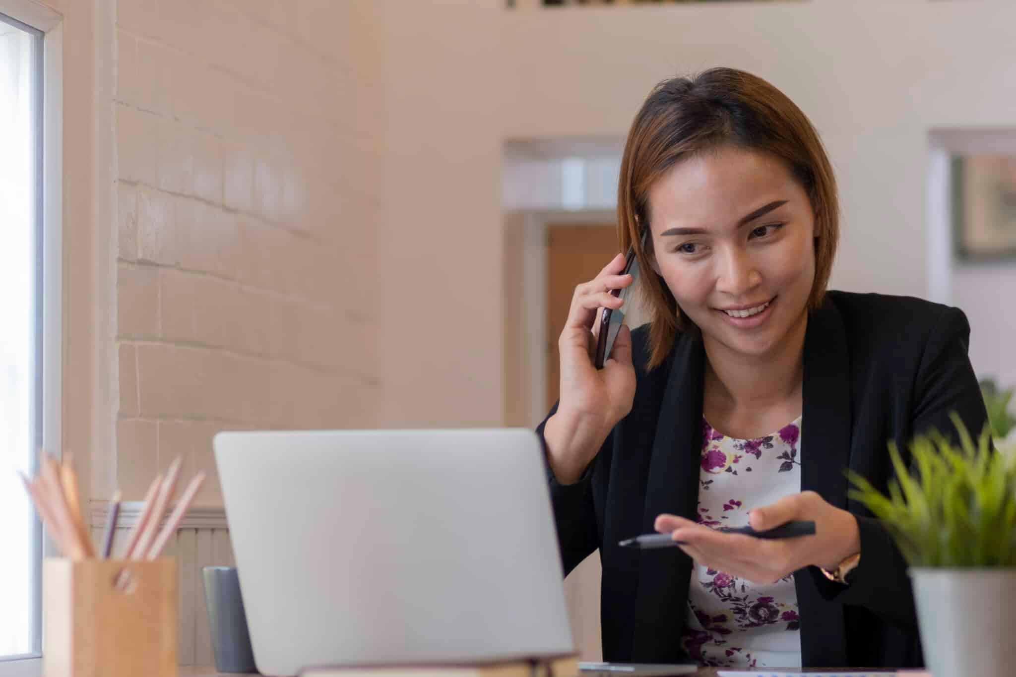 Person talking on phone and using laptop