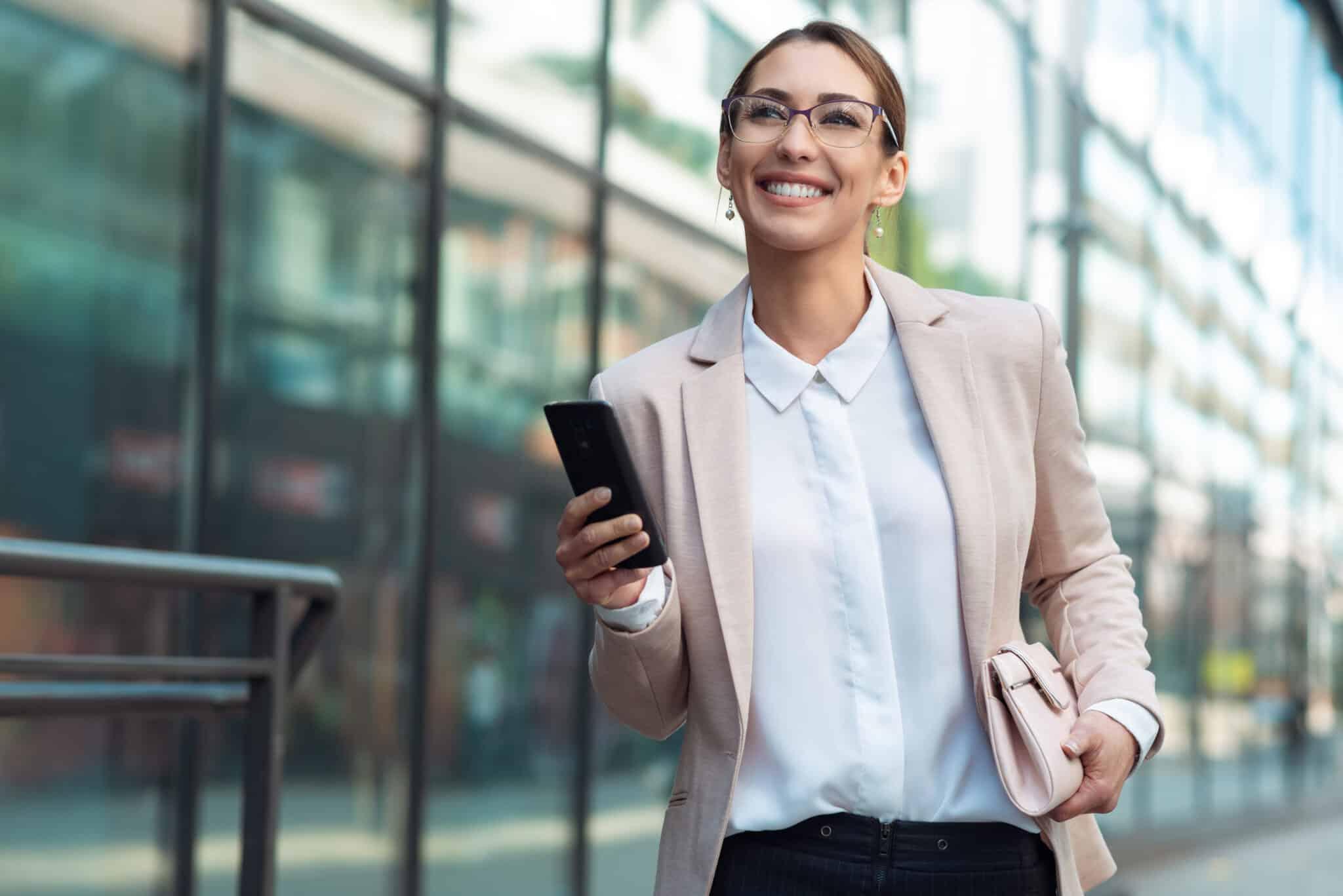 Professional in blazer smiling with smartphone