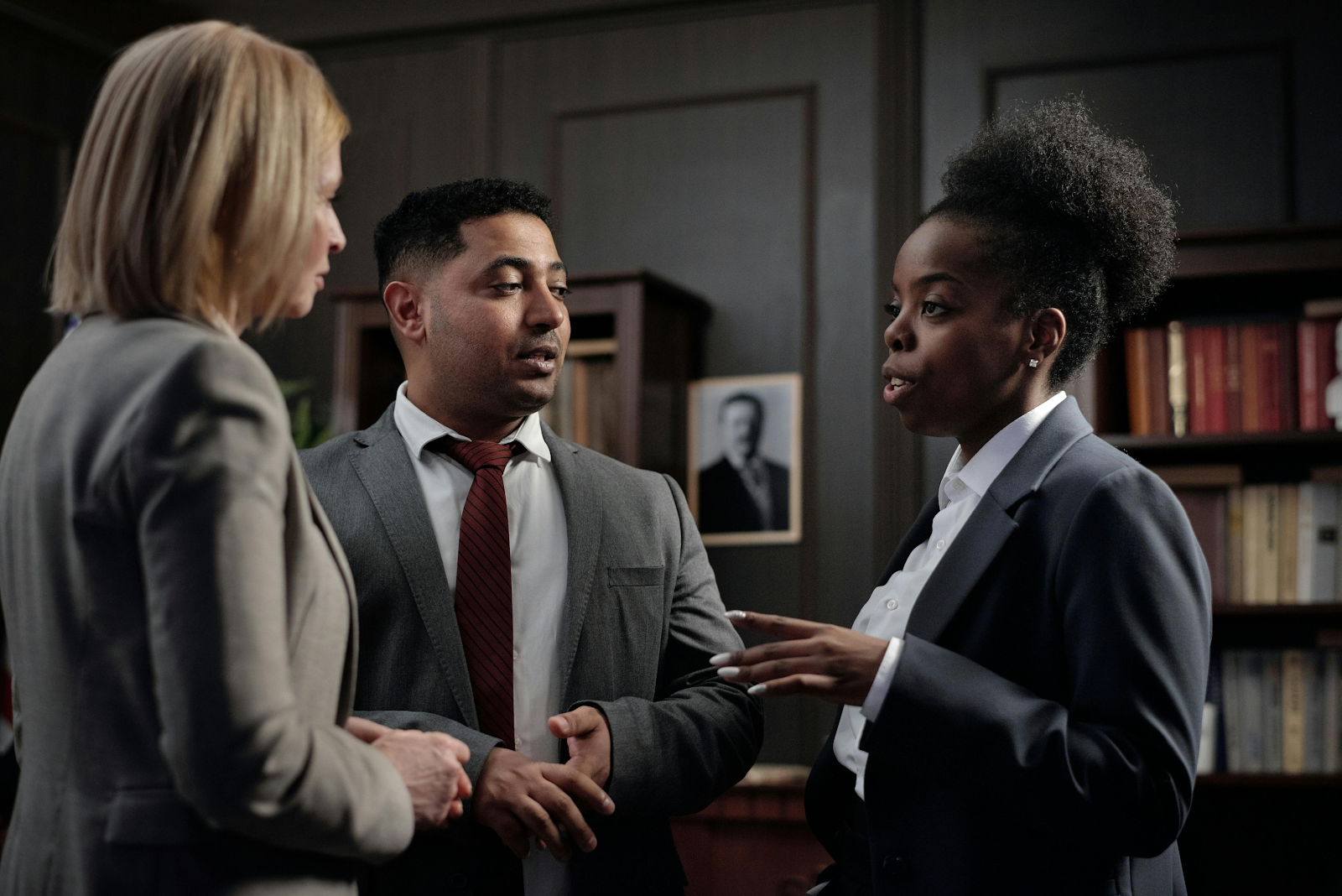 Three professionals discussing in an office setting.