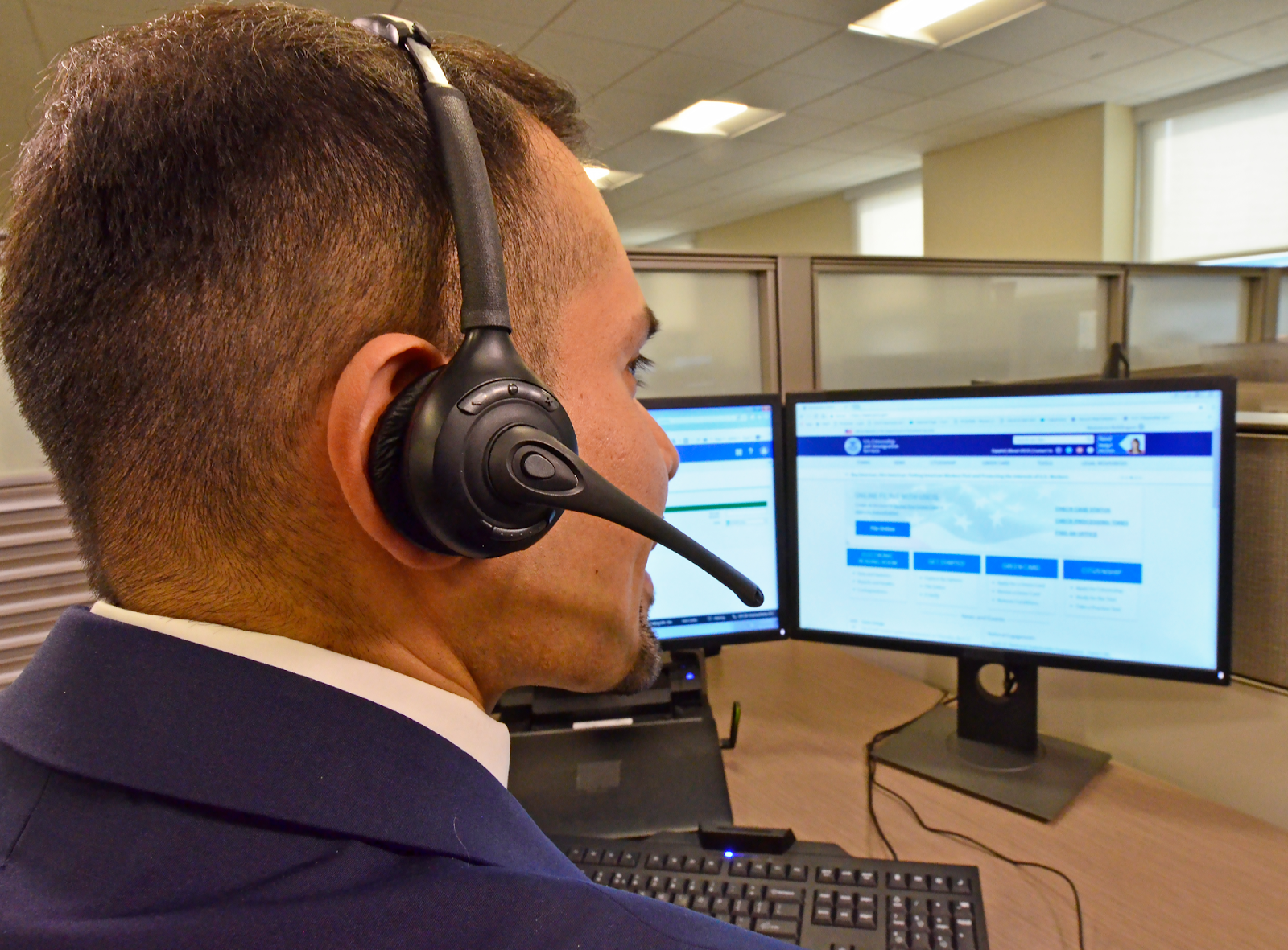 Person with headphones sitting in a desk at the USCIS contact center