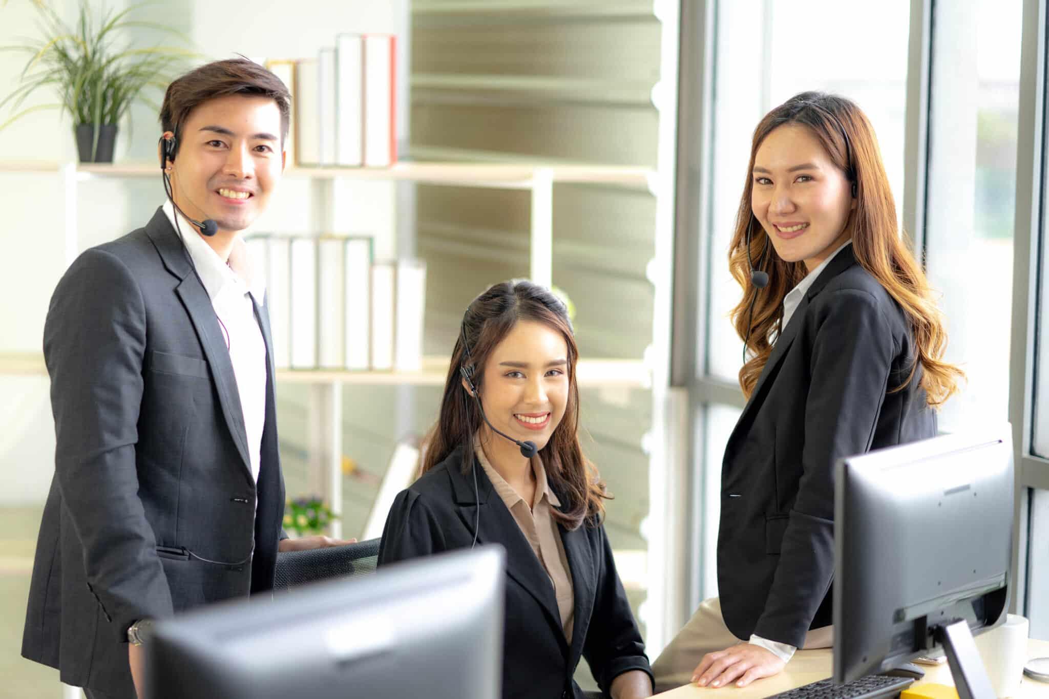 Three people smiling at computer monitors