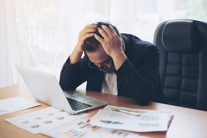 Man holding head in frustration at laptop