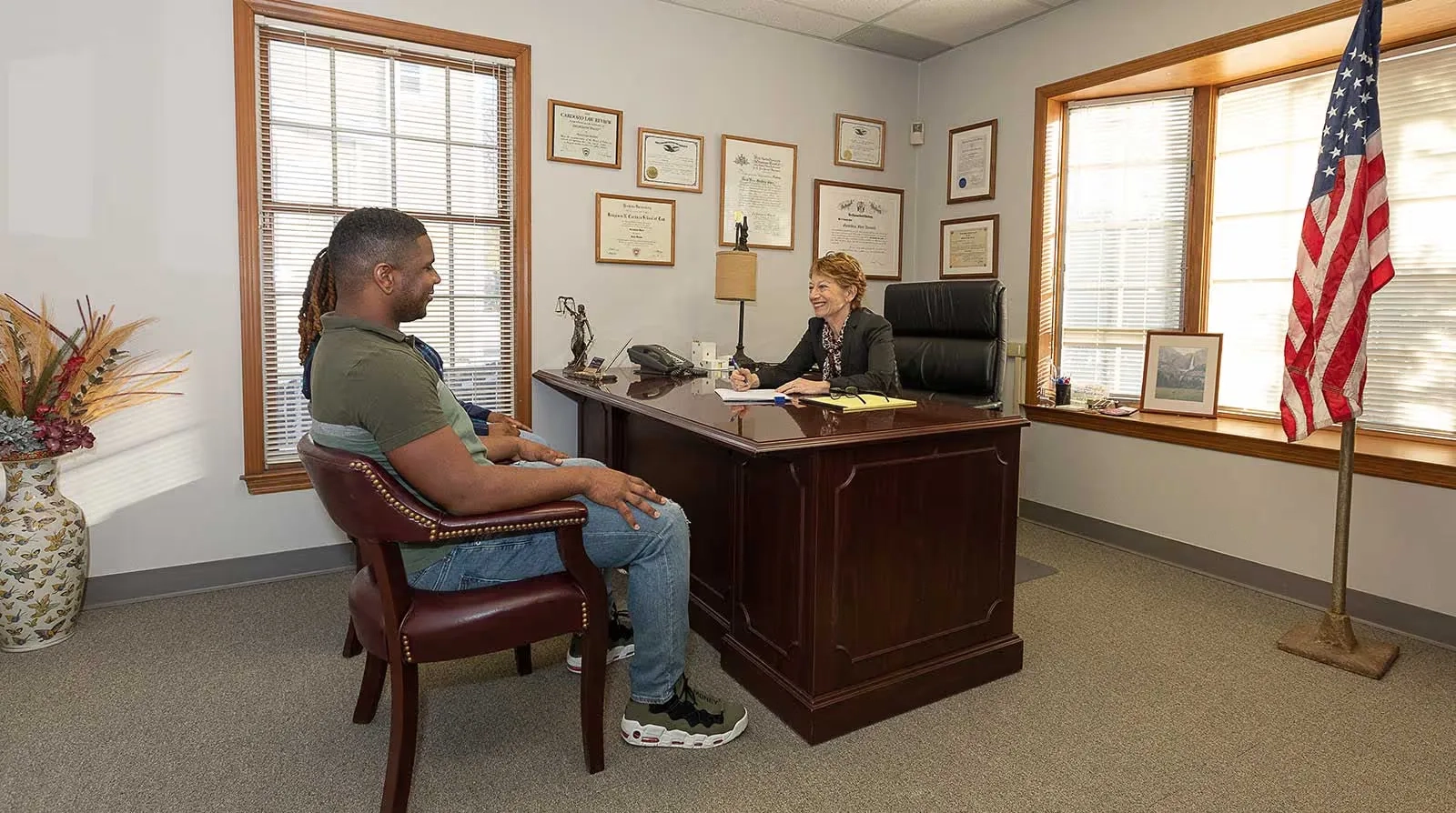 People sitting beside a desk and talking to a person