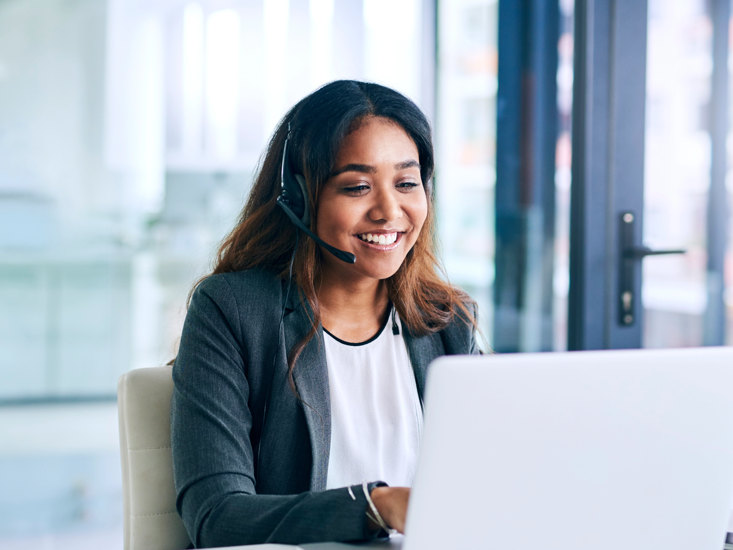 Woman smiling with headset at laptop