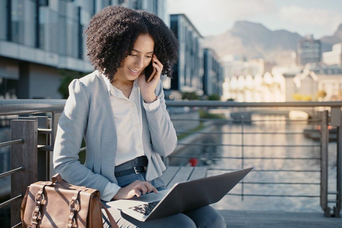 Person smiling on phone and laptop by water