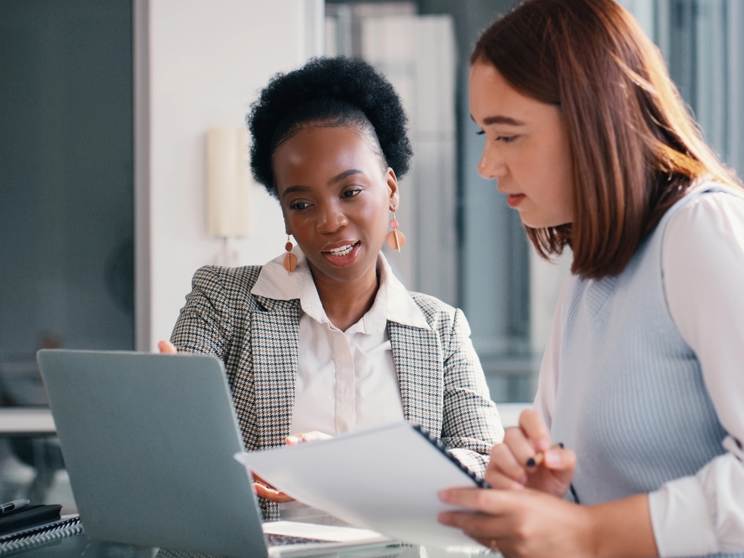Lawyer showing a paralegal how they use AI on their laptop
