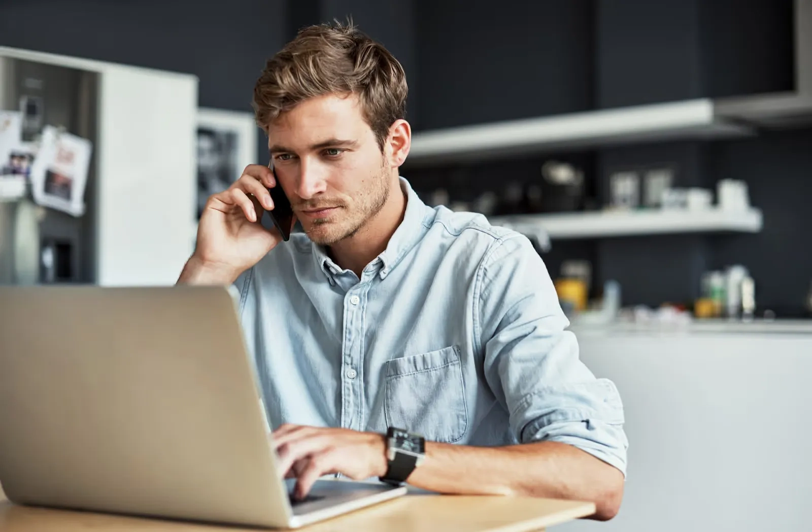 Person sitting in a desk in front of a laptop while talking on the phone
