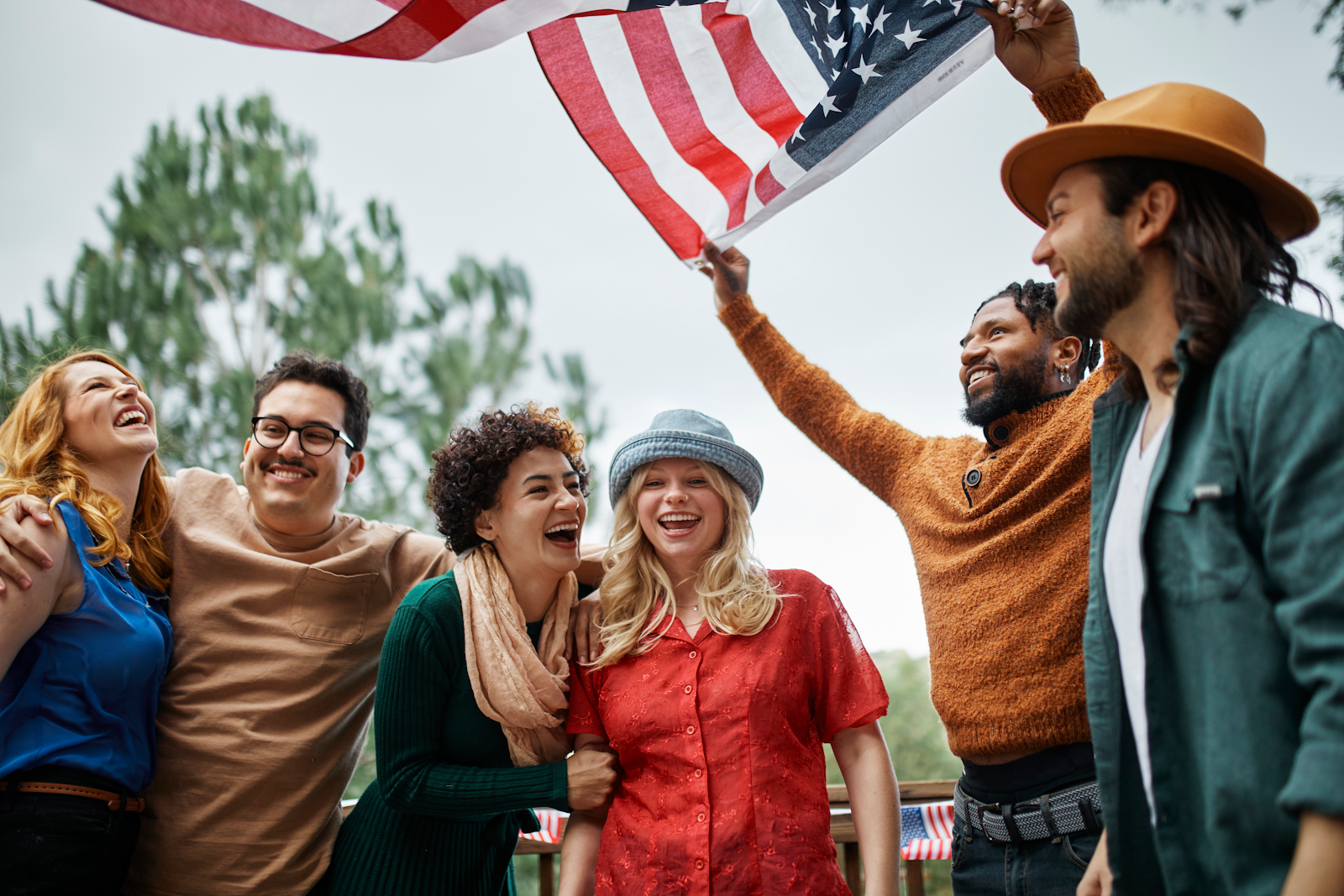 A diverse group of individuals proudly holding an American flag.
