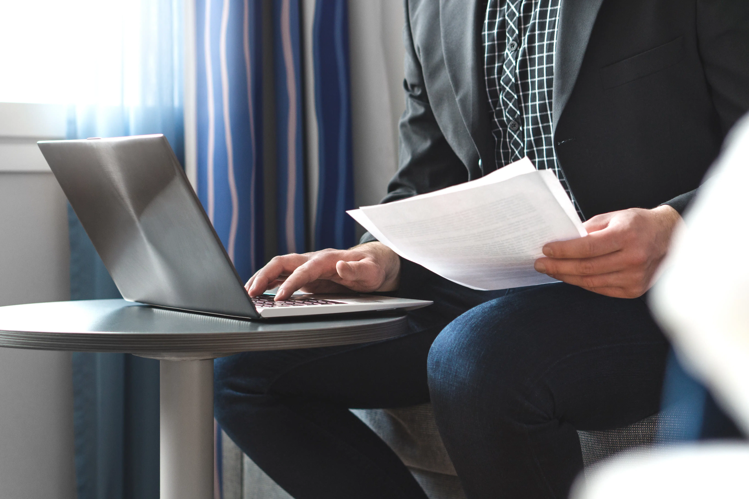 person at laptop reading paper