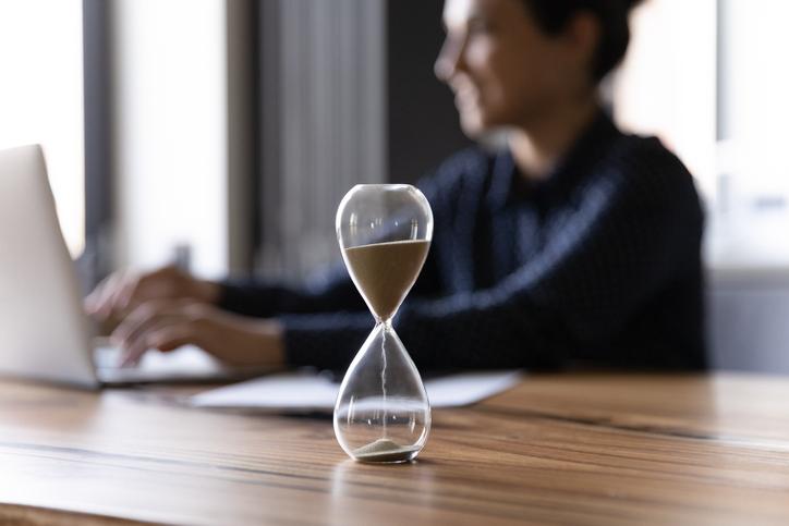 Person working on laptop behind hourglass