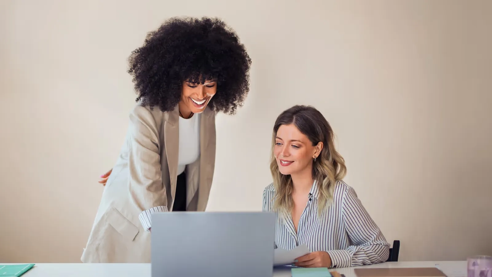 two women speaking at computer desk