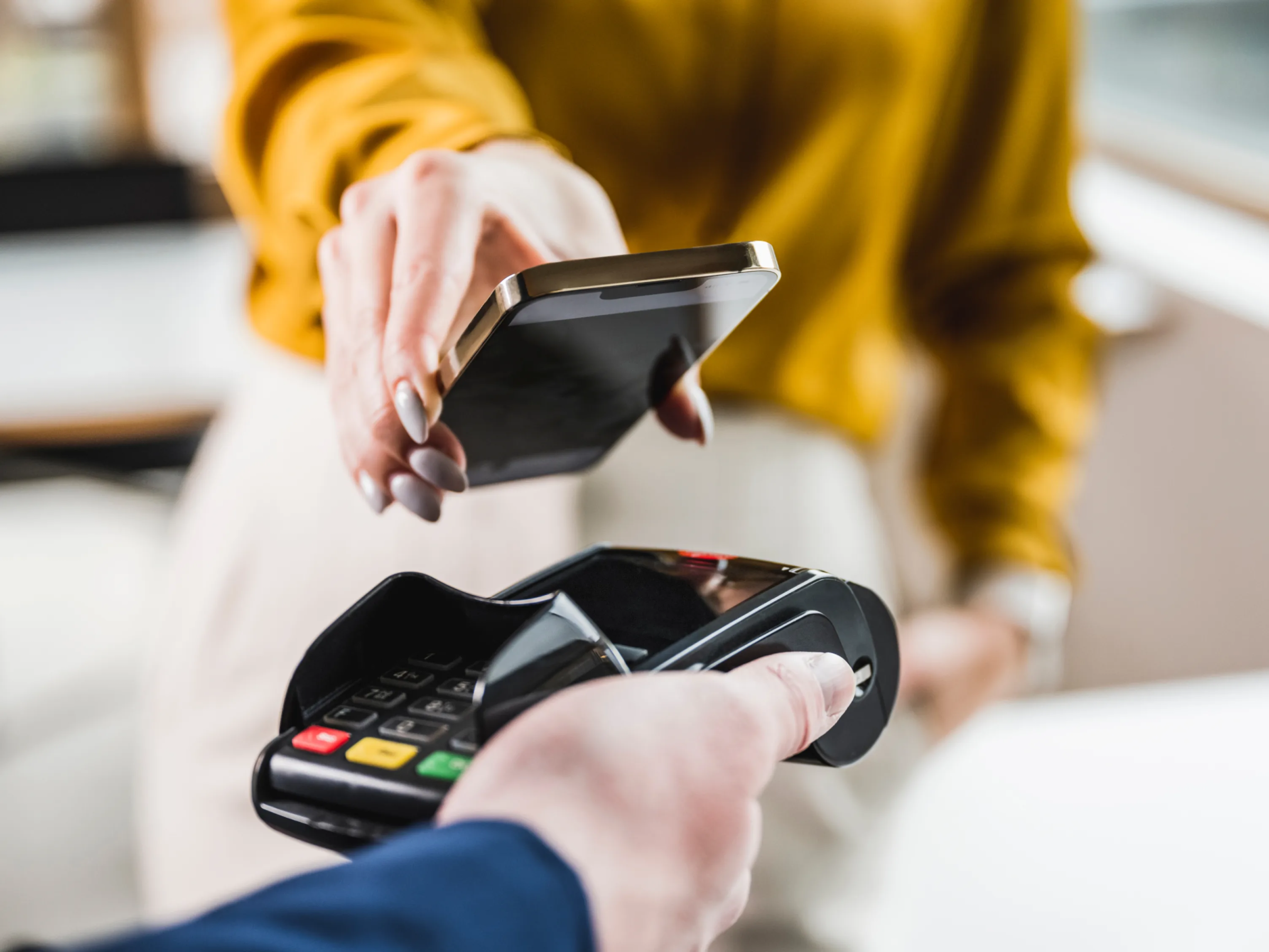 A client uses their phone to tap-to-pay on a payment terminal.