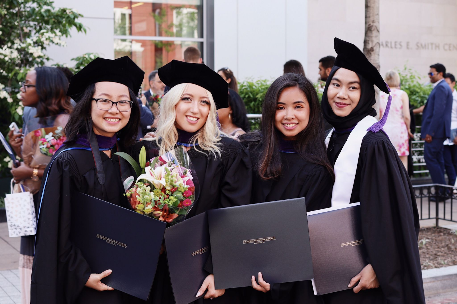 Group of graduates in cap and gown, standing together for a graduation photo.