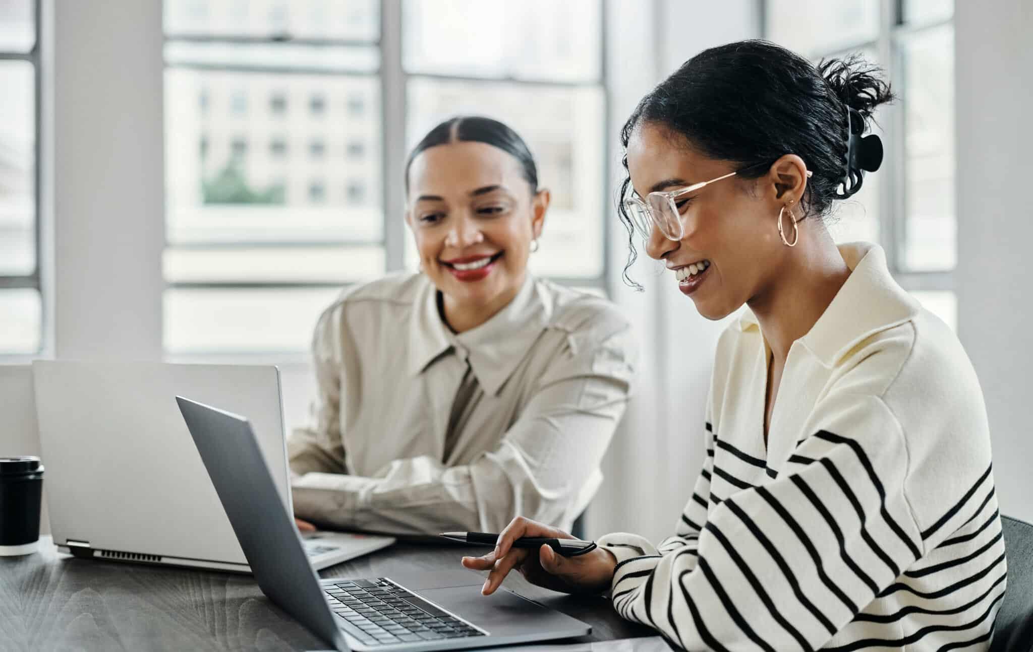 Two people smiling and working at a laptop