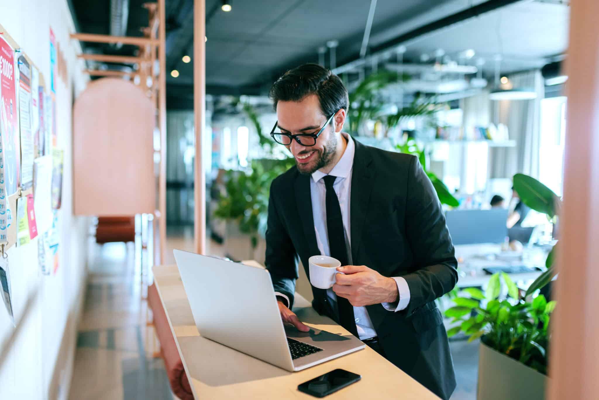 Person smiling at laptop with coffee