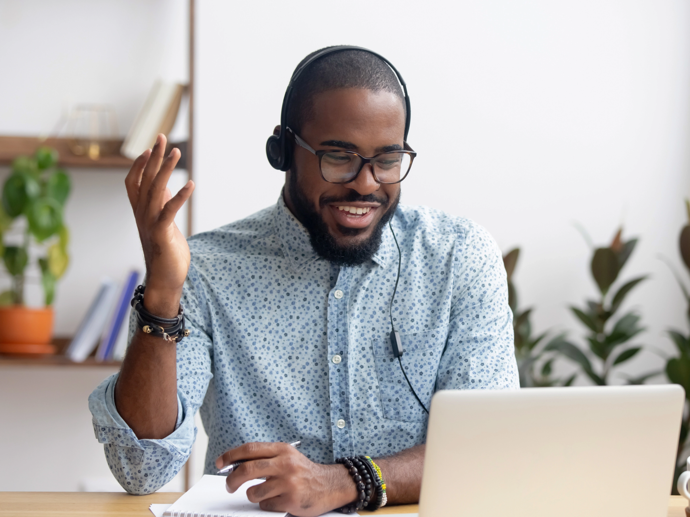 man smiling with headset at laptop