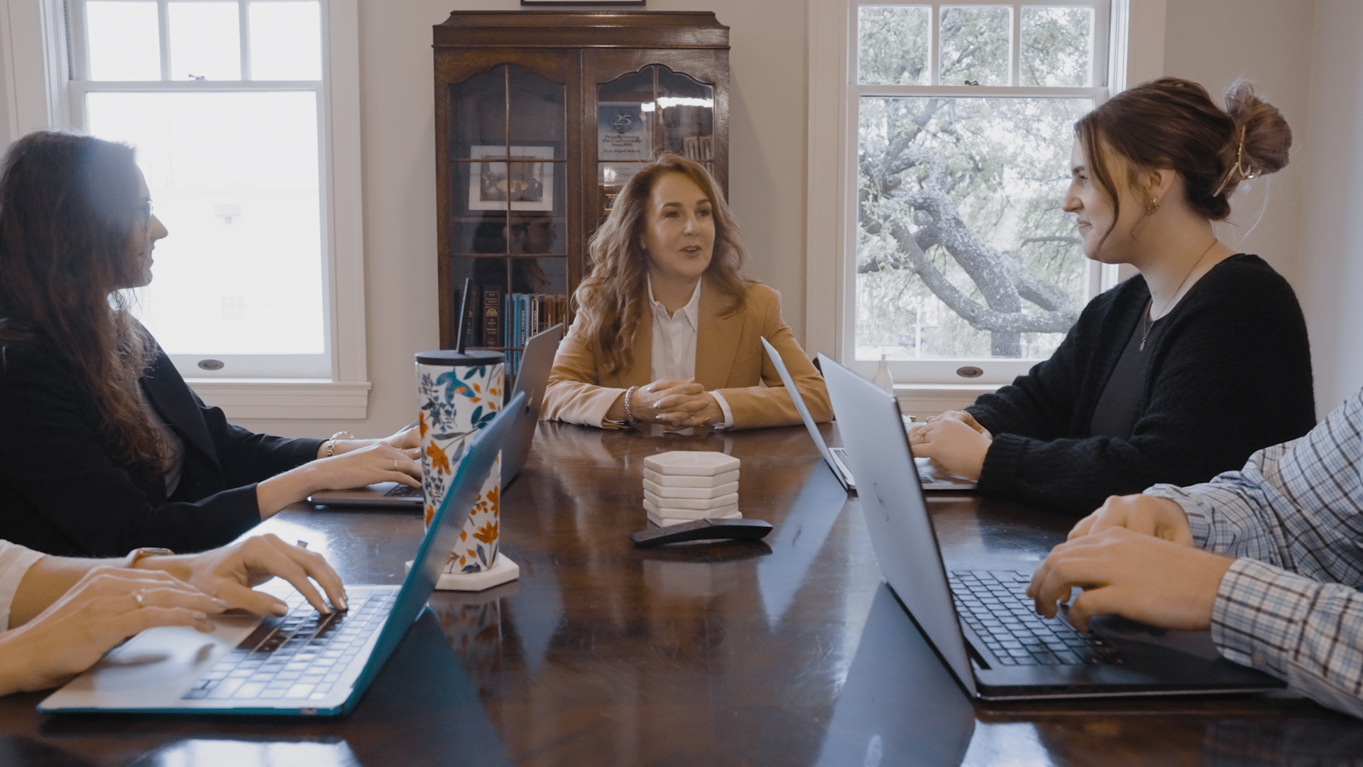 Clients and lawyers in meeting room talking over laptops