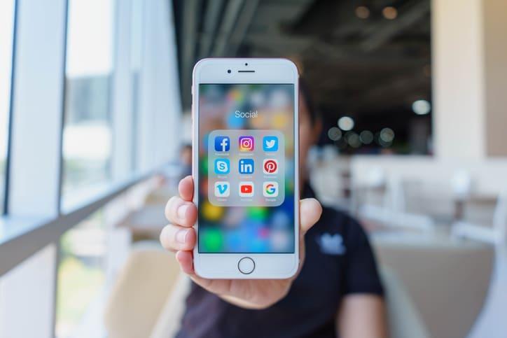 Person holding smartphone with social media apps displayed