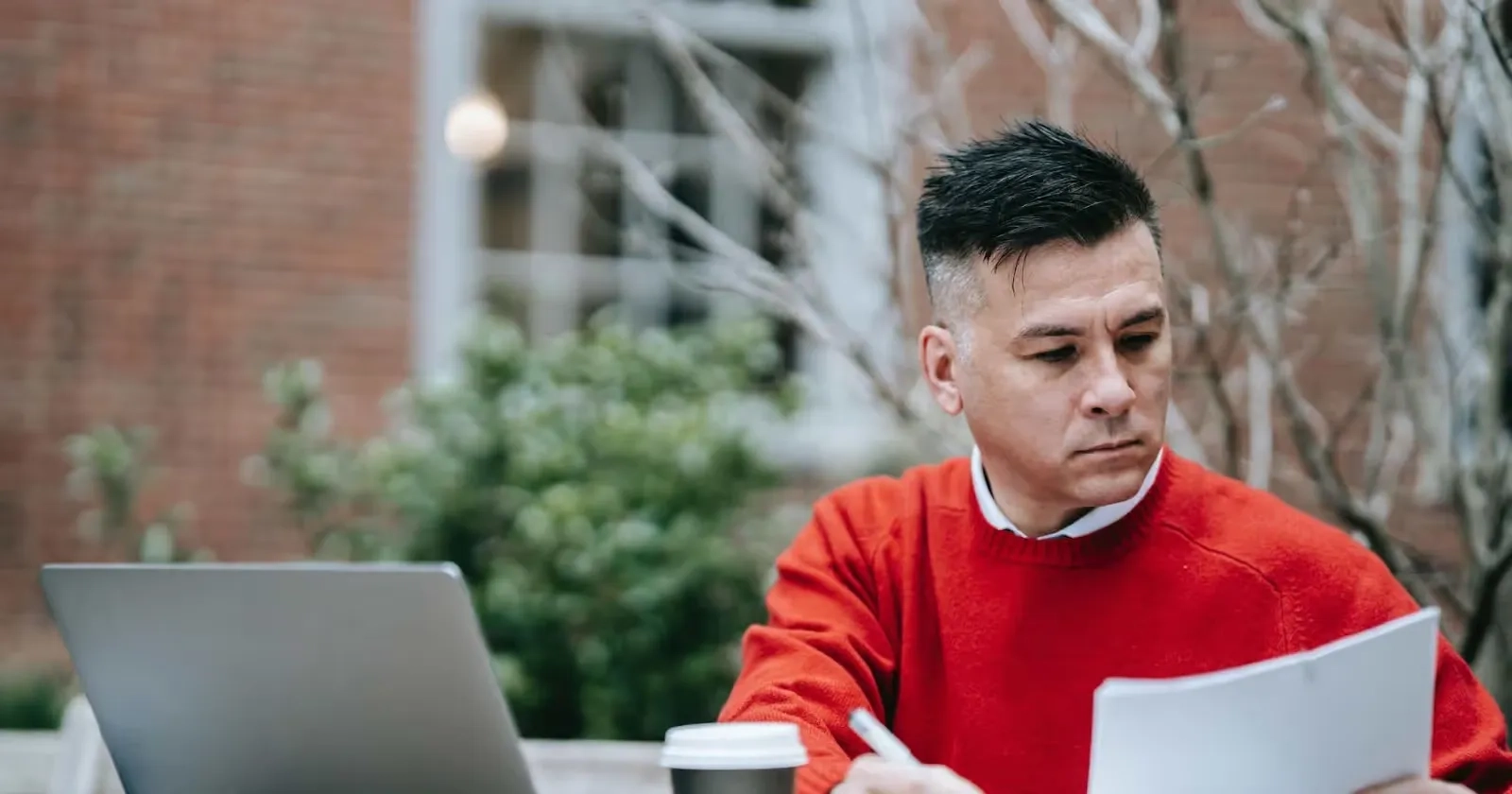 man reading documents in front of his computer while being outside