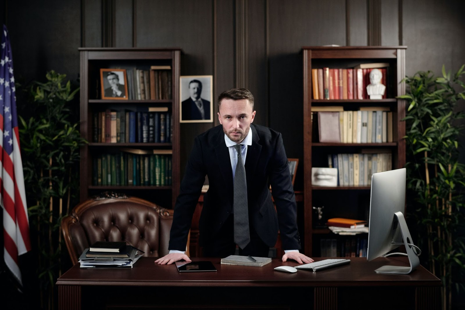 lawyer with serious look standing behind his desk and with an American flag