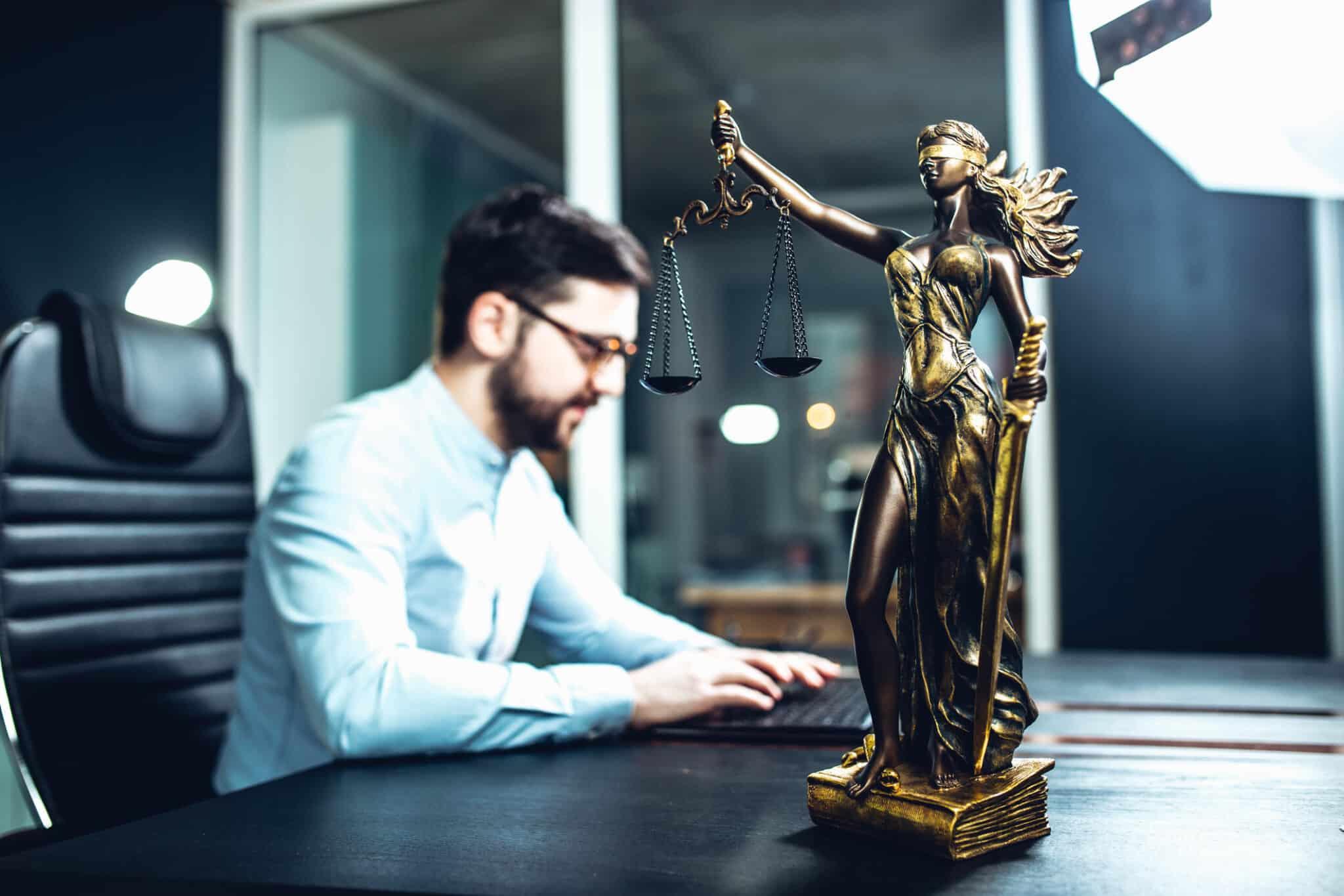 Person working at laptop with justice scales on desk