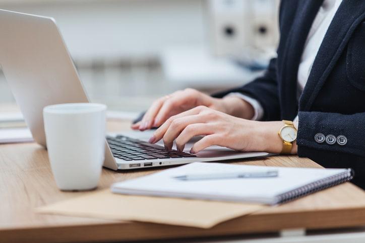 Person typing on laptop with coffee on the table