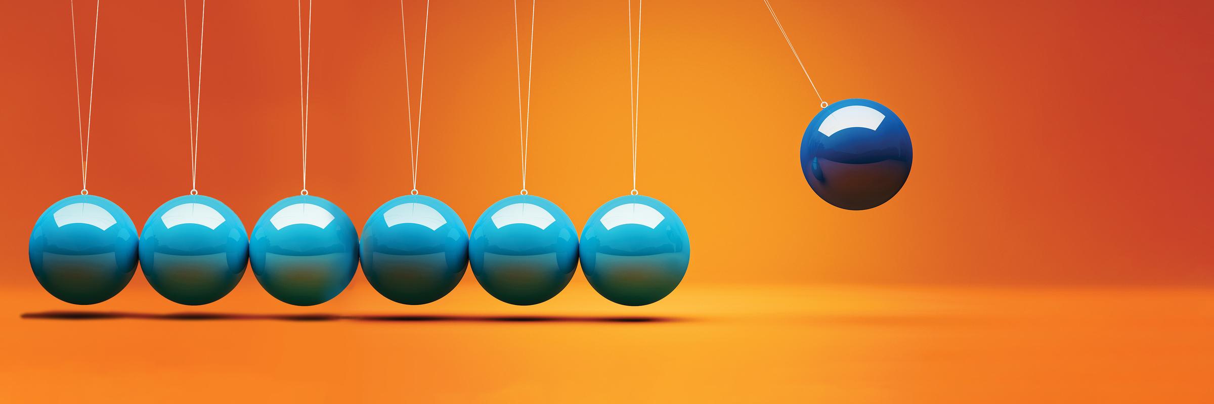 Blue and aqua kinetic balls swinging against a bright orange background, suggesting momentum