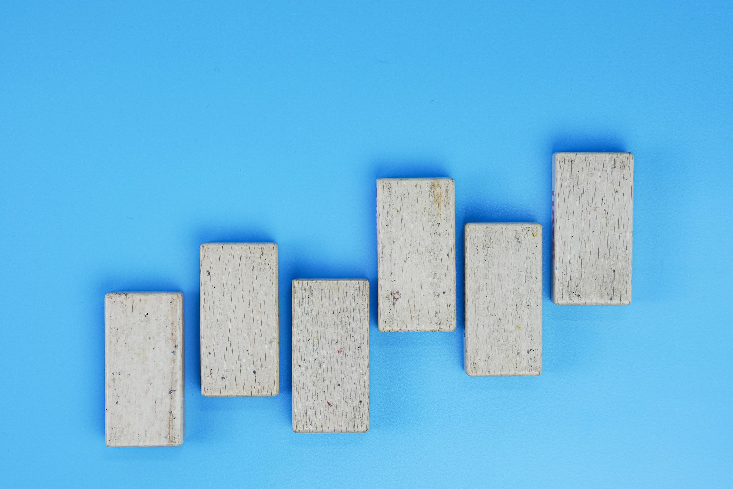 Wooden blocks arranged to mimic the ups and downs of a graph, against a blue background.