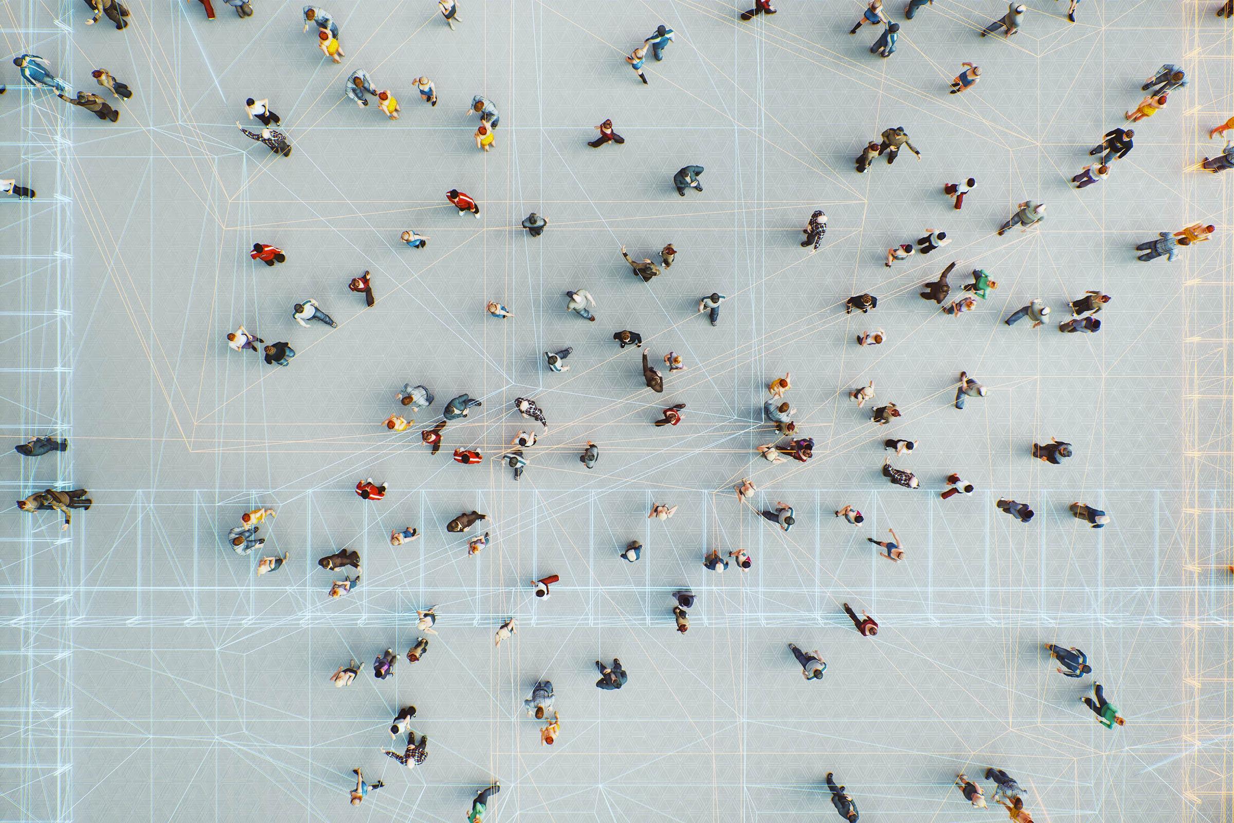 Viewed from high above, dozens of people in colorful clothing meander across a floor lined with interconnected, geometrical lines.