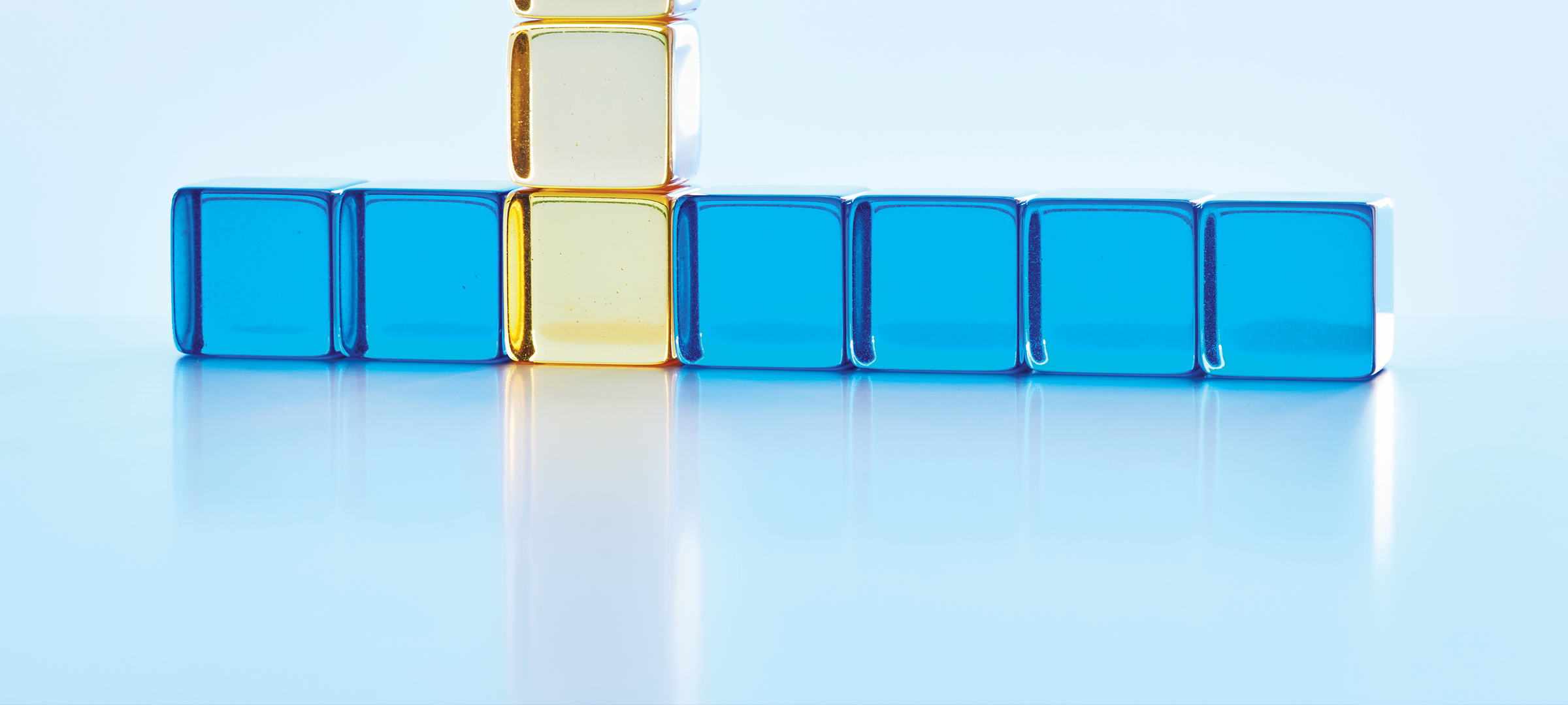 A row of bright blue glass squares are intersected by a vertical line of clear gold squares, representing a rising trend.