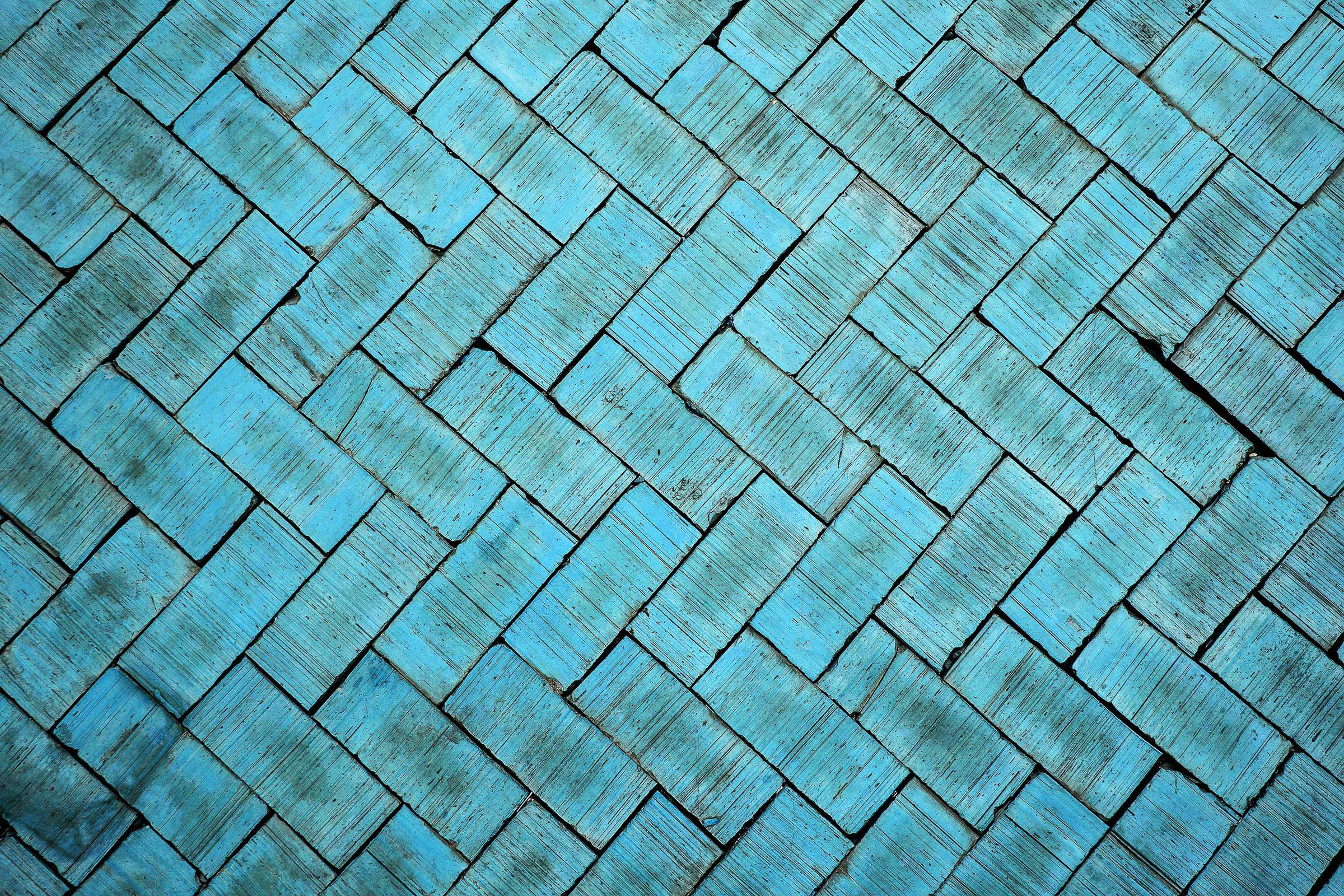 Bright turquoise bricks, with unique markings caused by age, are laid in an eye-catching chevron pattern across the entire photo.