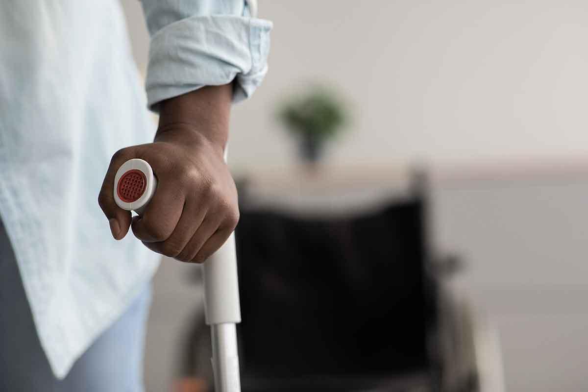 Close up view of the hand of someone holding the handle of a crutch following a hip replacement.
