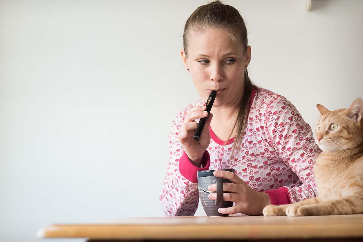 woman vaping with cat nearby