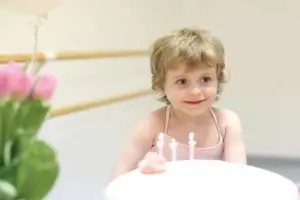 Little girl with 3 birthday candles in front of her