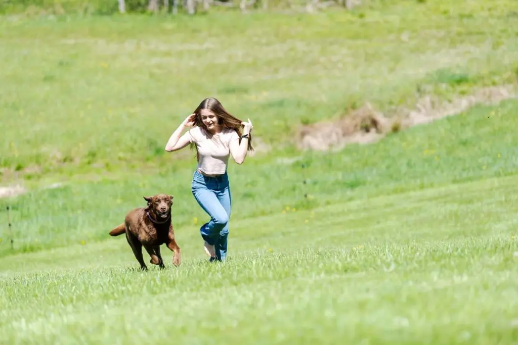 Anna runs barefoot up hill with dog behind her