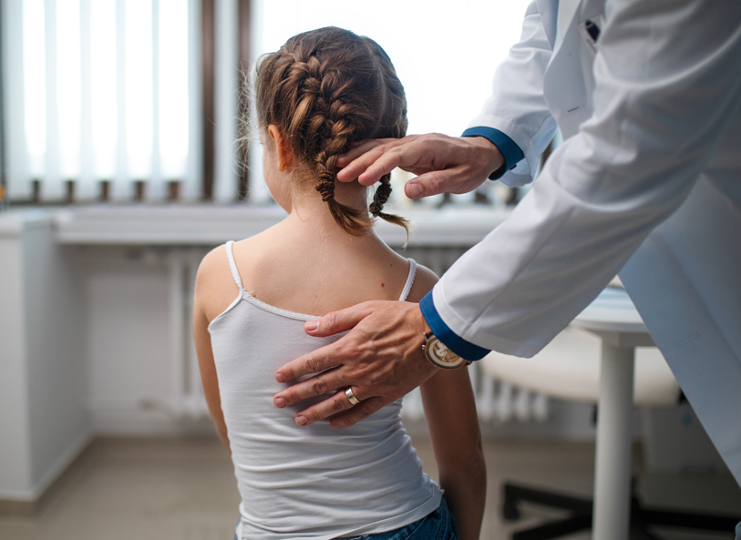 young girl's pediatrician checks her for scoliosis