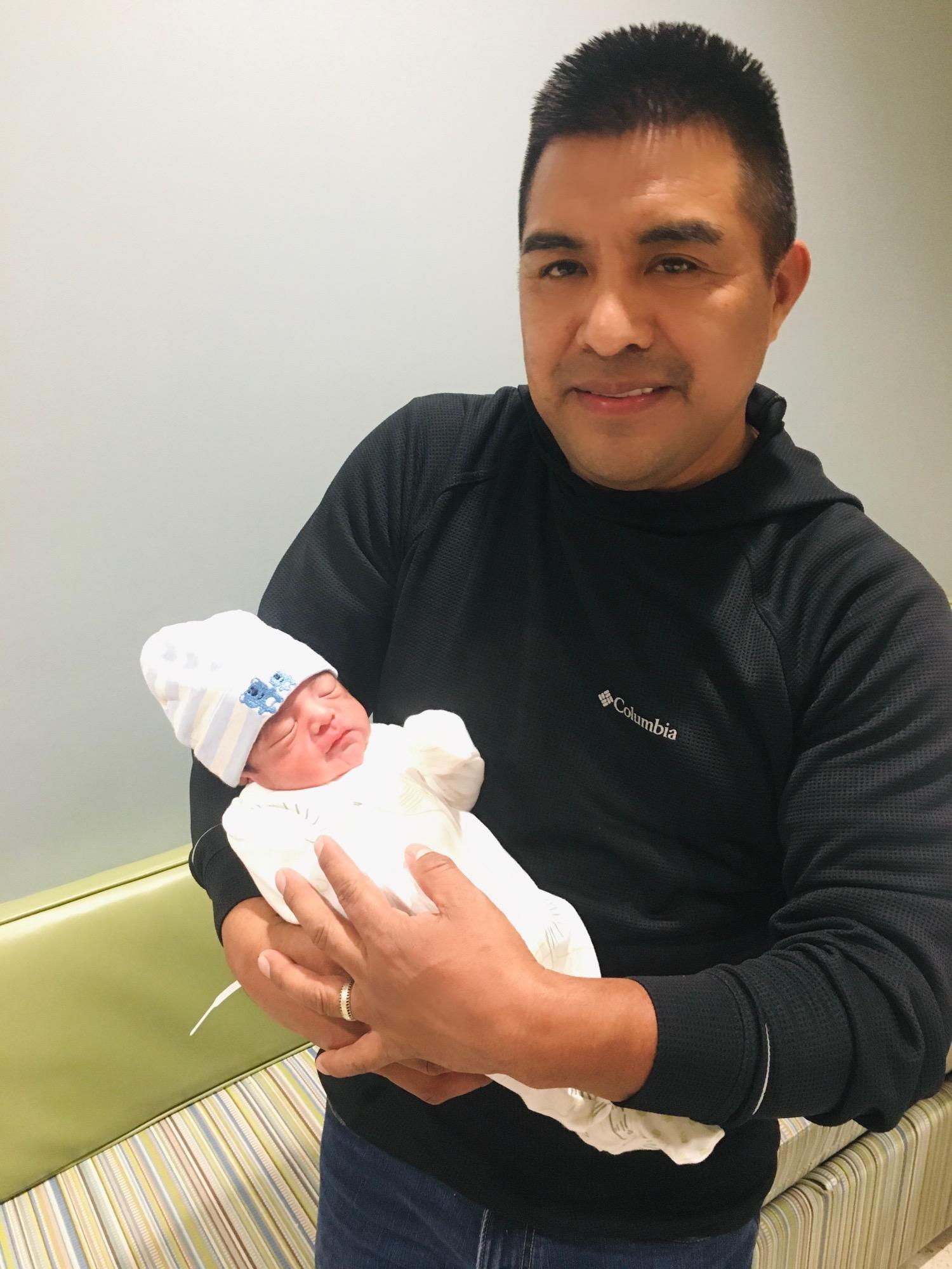 Proud dad holds up newborn 