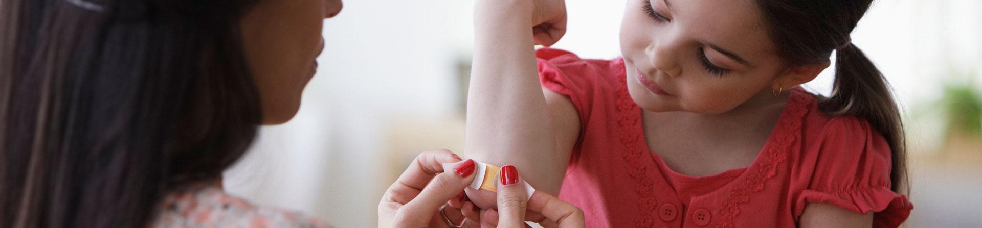 little girl getting a bandage on her elbow