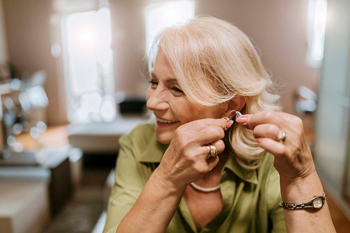 older woman holding a hearing aid