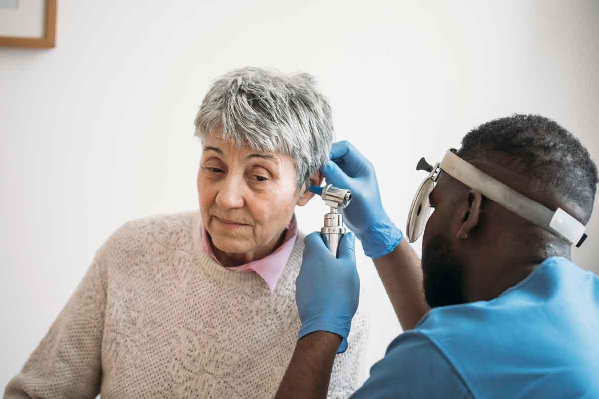 A woman having her ear checked for tinnitus with a medical instrument.
