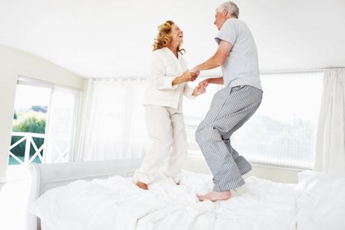 husband and wife jumping on the bed