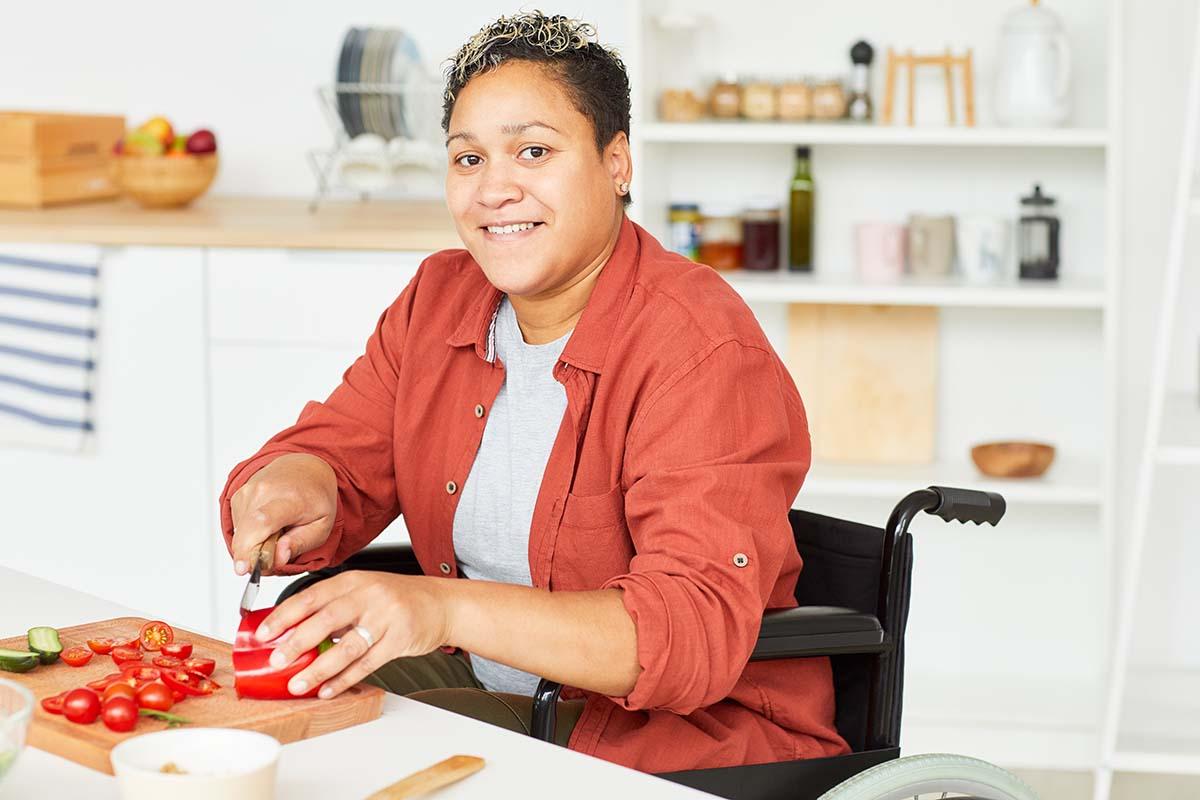 A person in a wheelchair chops vegetables
