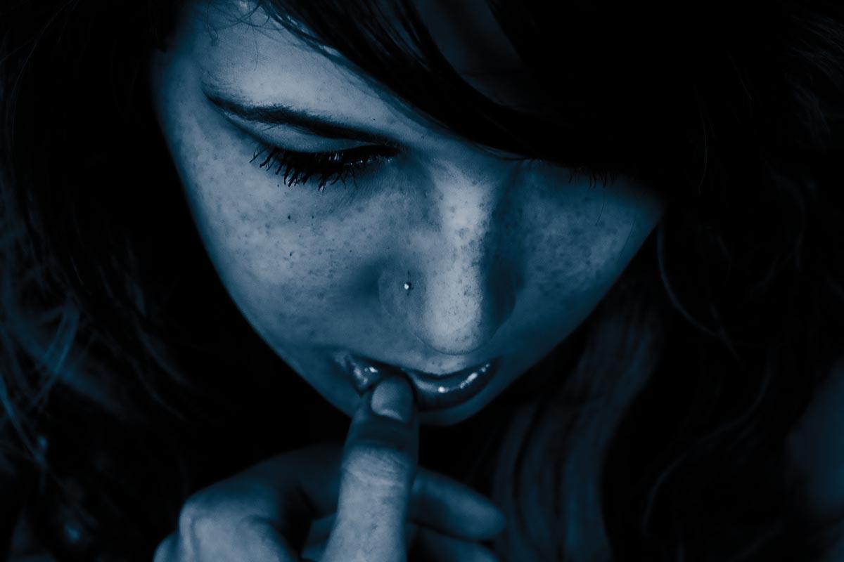 teen girl with her head lowered, hands touching face