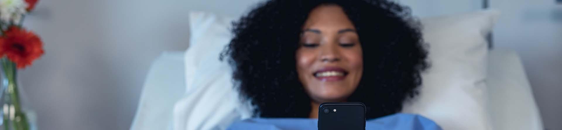 Woman on phone while in hospital bed