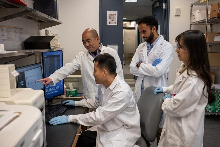Jie Sun, PhD, points out important data to members of his lab team as they work to understand the causes of persistent COVID-19 lung problems.