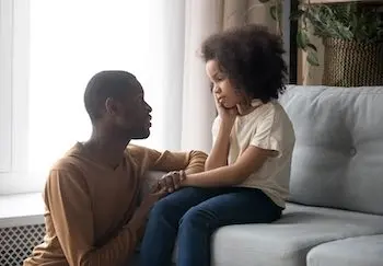father talking to his daughter on the couch
