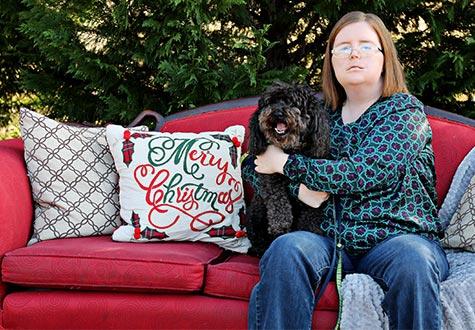 Abby Loden and her dog, London, sitting on a couch